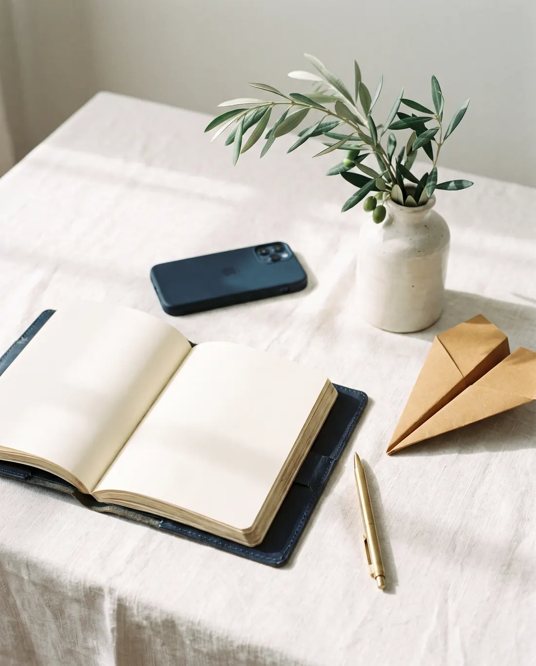 Escritorio con agenda abierta, teléfono y un avión de papel